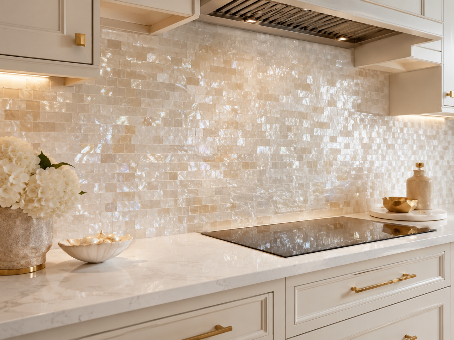Elegant kitchen backsplash with mother of pearl mosaic tile, soft iridescent shell texture, white cabinets, light countertop, and warm modern interior lighting
